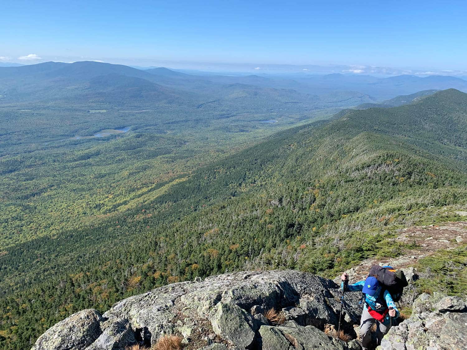 Woman hiking up steep rocky trail with green mountains