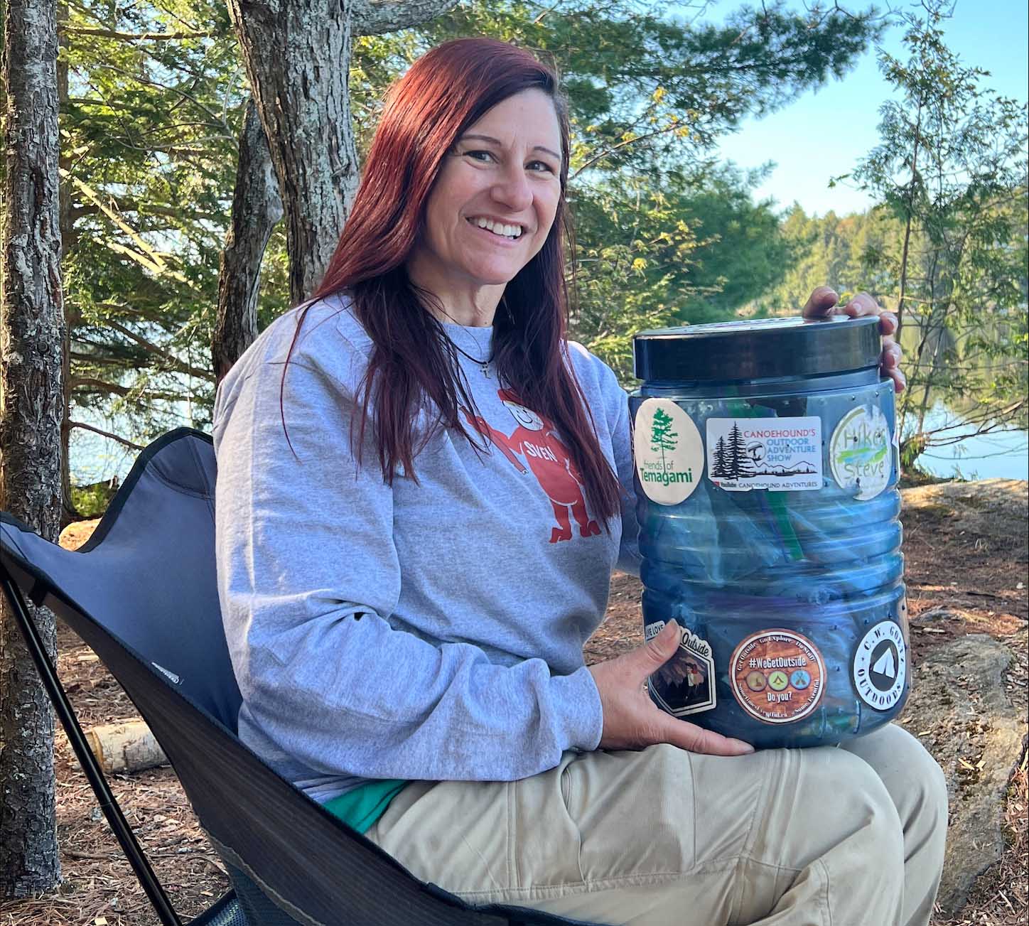 Woman sits with Bear Canister in Camp Chair