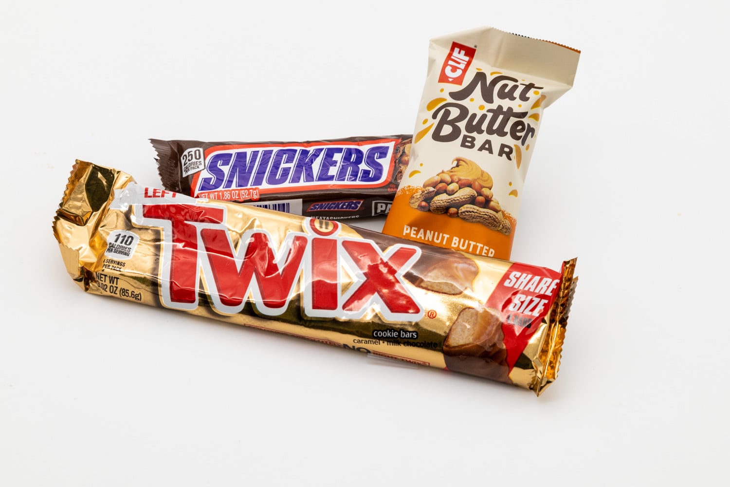 A twix bar, a snickers bar, and a clif nut butter bar