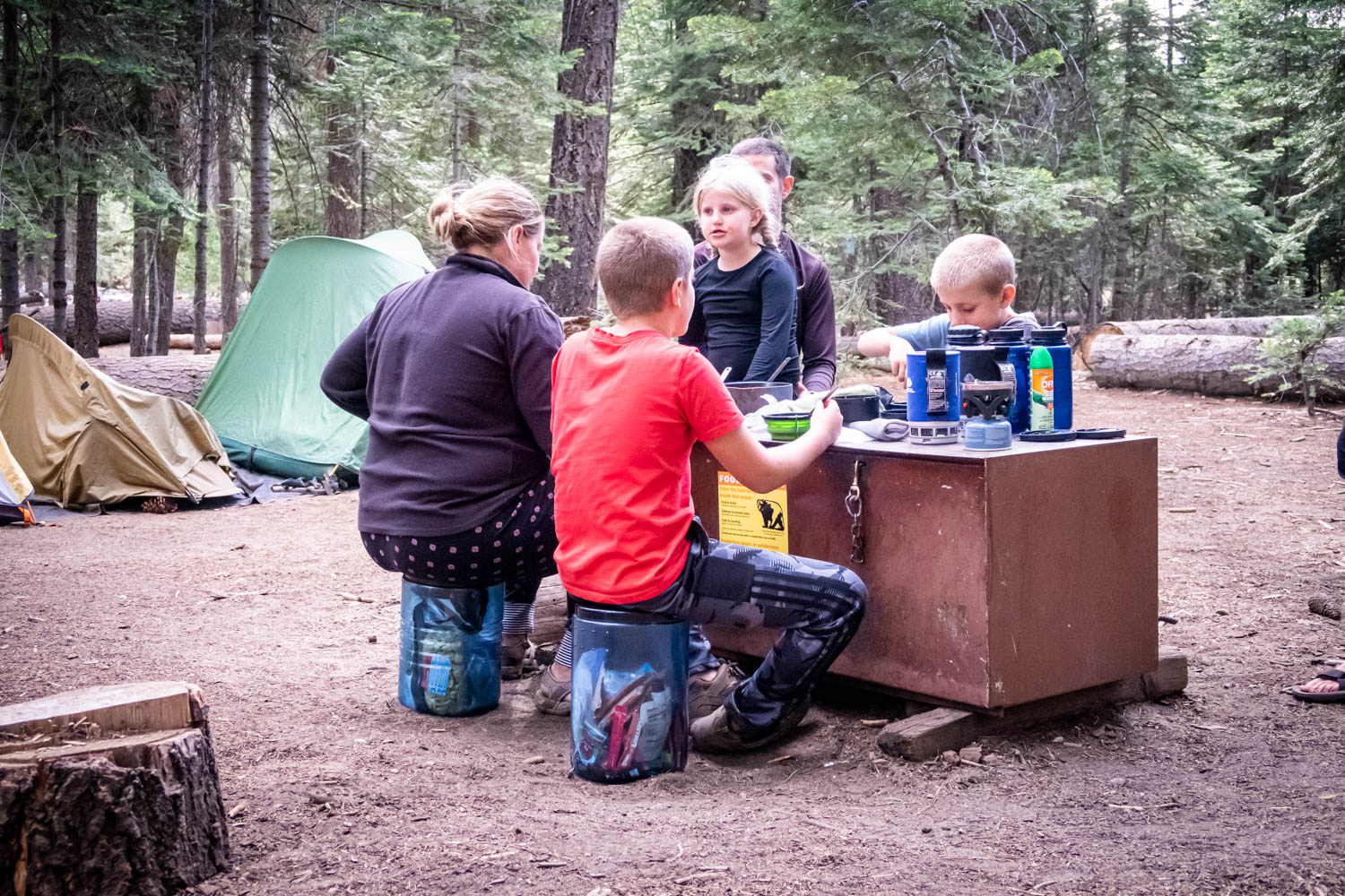 A family eats dinner around a bear proof locker