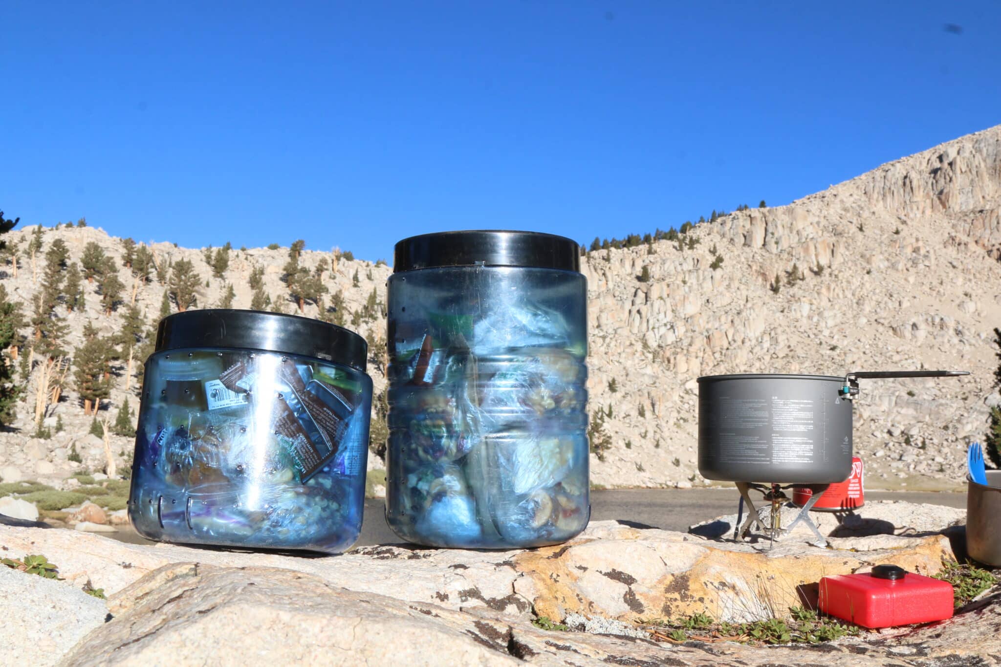 An image of BearVaults next to a alpine lake while cooking breakfast.