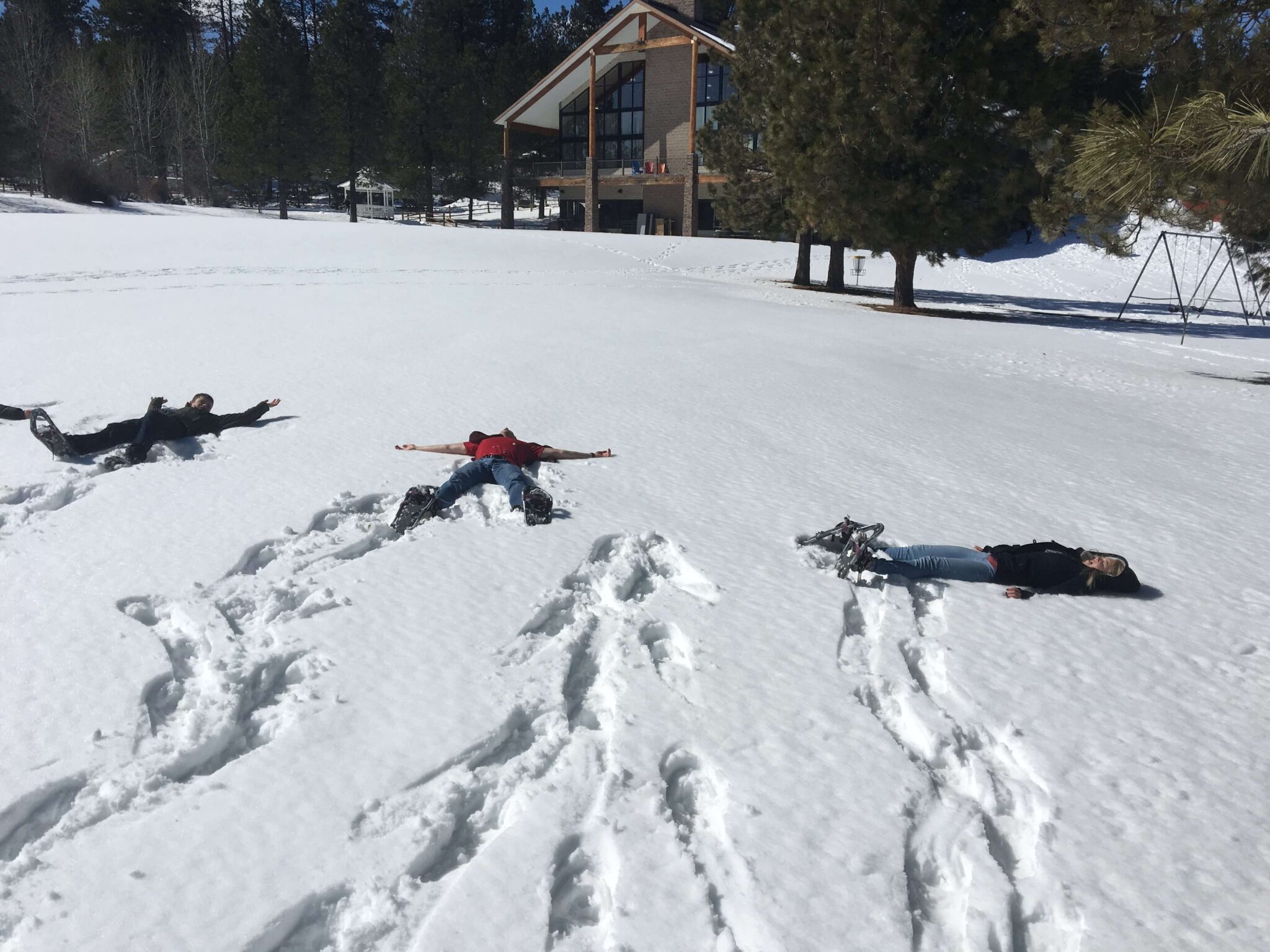 people lying down in a sunny patch of snow